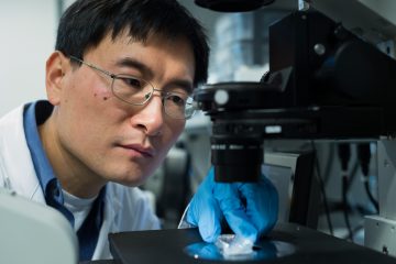 Dr. Hongshen Ma inspects a microscope.