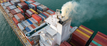 Aerial view of a containership, with exhaust coming out the top.