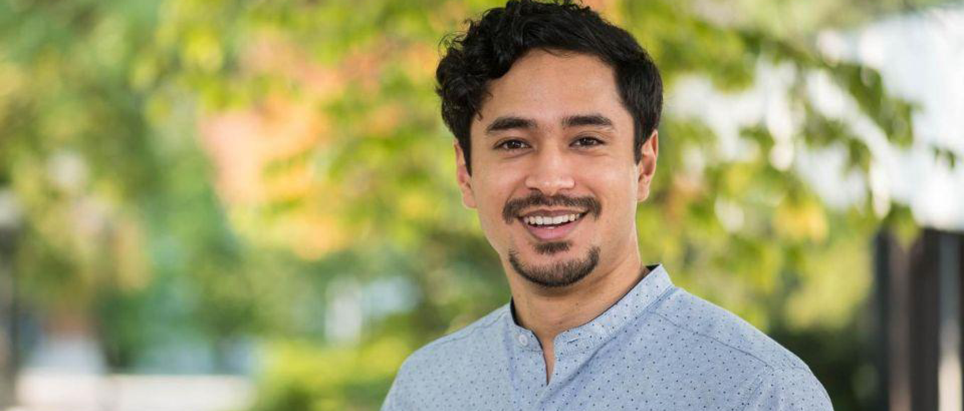 Dr. Pranav Shrestha, recent MECH PhD graduate, smiles at the viewer. He stands in front of a tree on a sunny day.