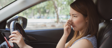 Woman in car experiencing bad smell