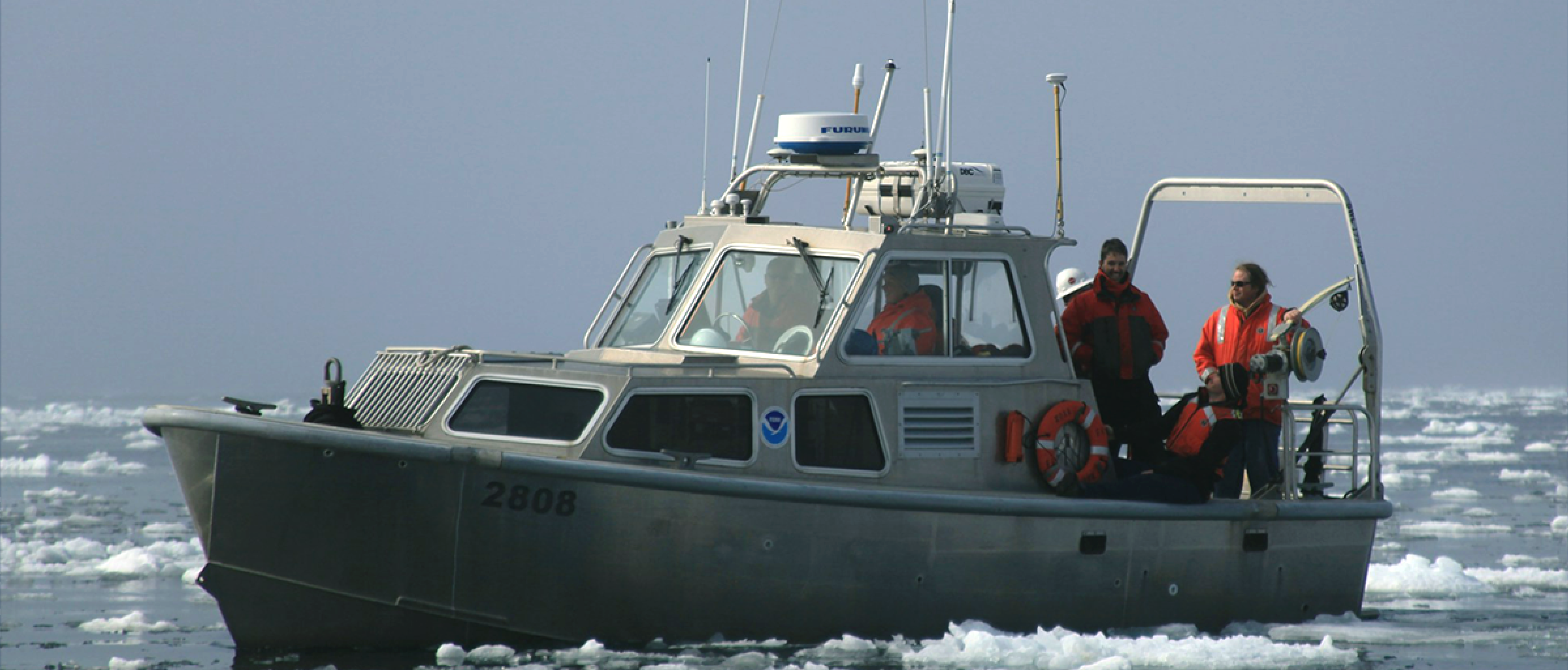 People on a boat navigate an icy ocean.