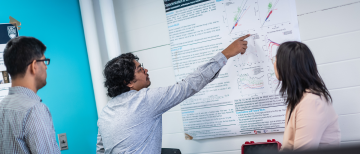 Image of a graduate student demonstrating their project poster